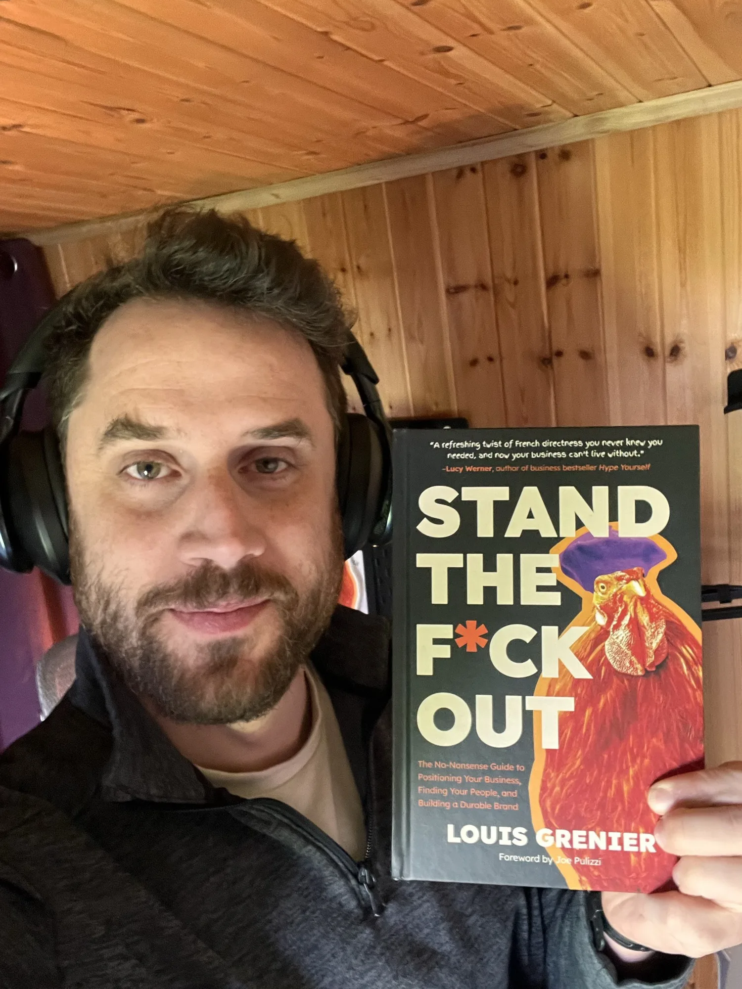 Louis Grenier holding his book Stand The F*ck Out